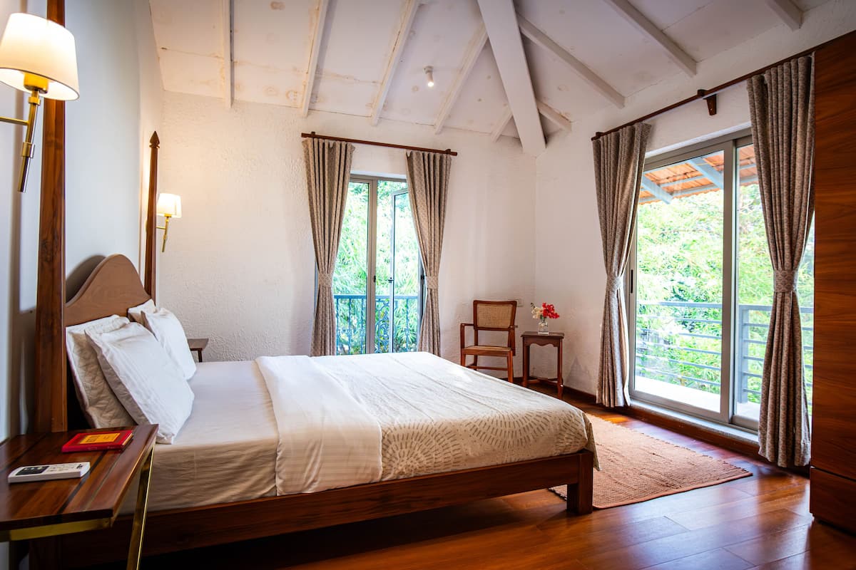 A bedroom with a wooden bed, a nightstand, a chair, and a window with curtains.