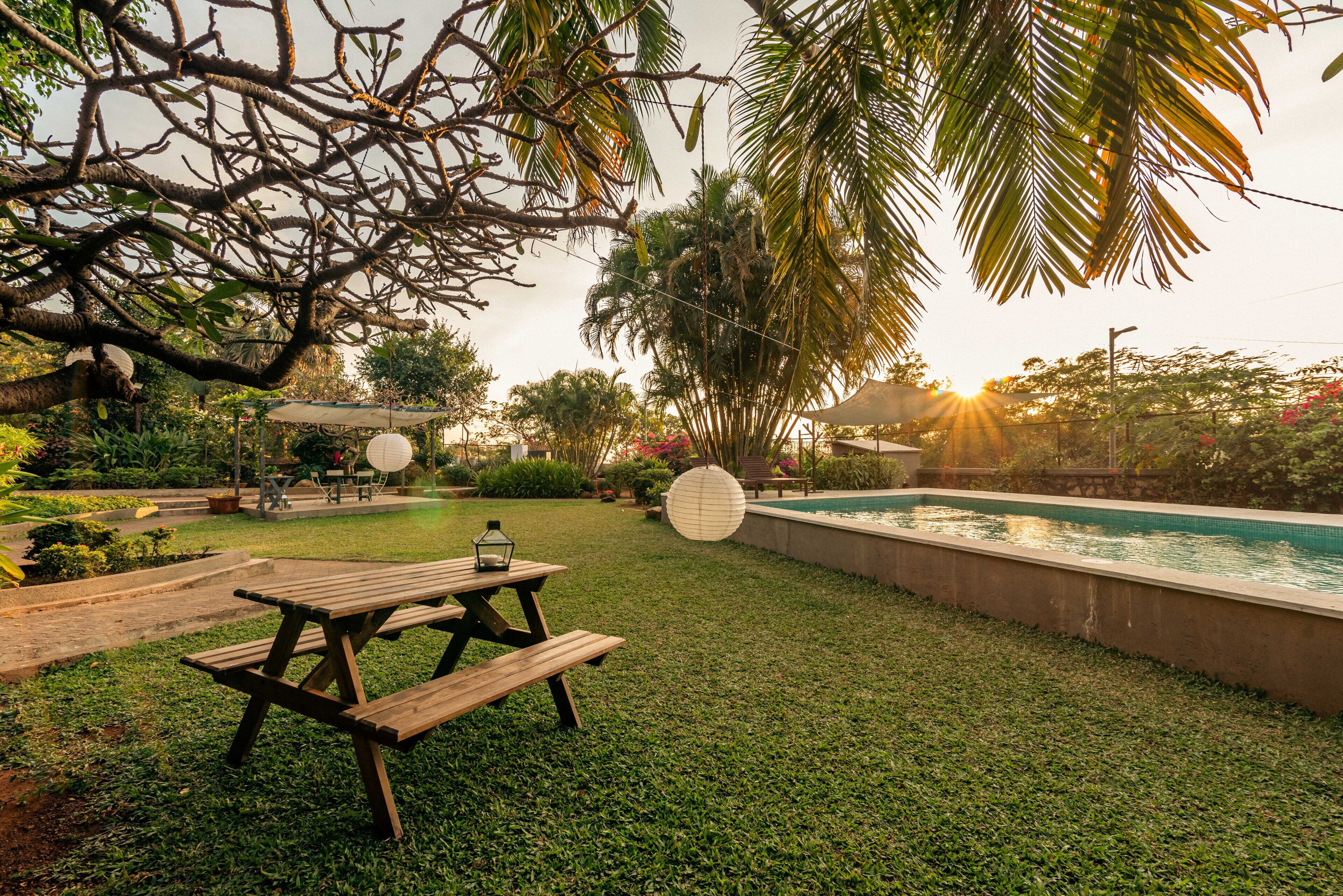 Ein Garten mit einem Holztisch, einem Swimmingpool und Palmen.