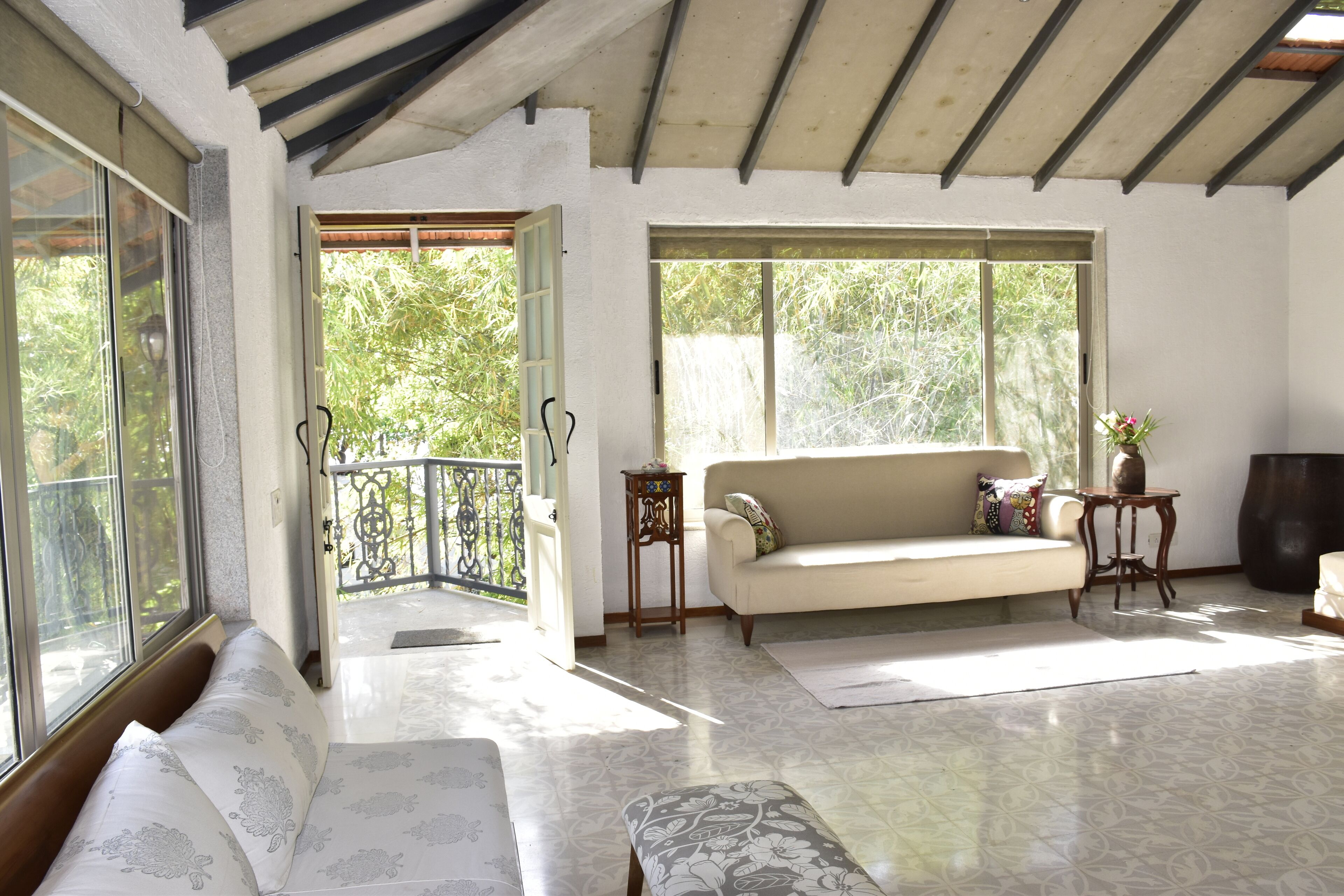 A spacious living area with a sofa, a bench, and a large window providing a view of greenery outside.