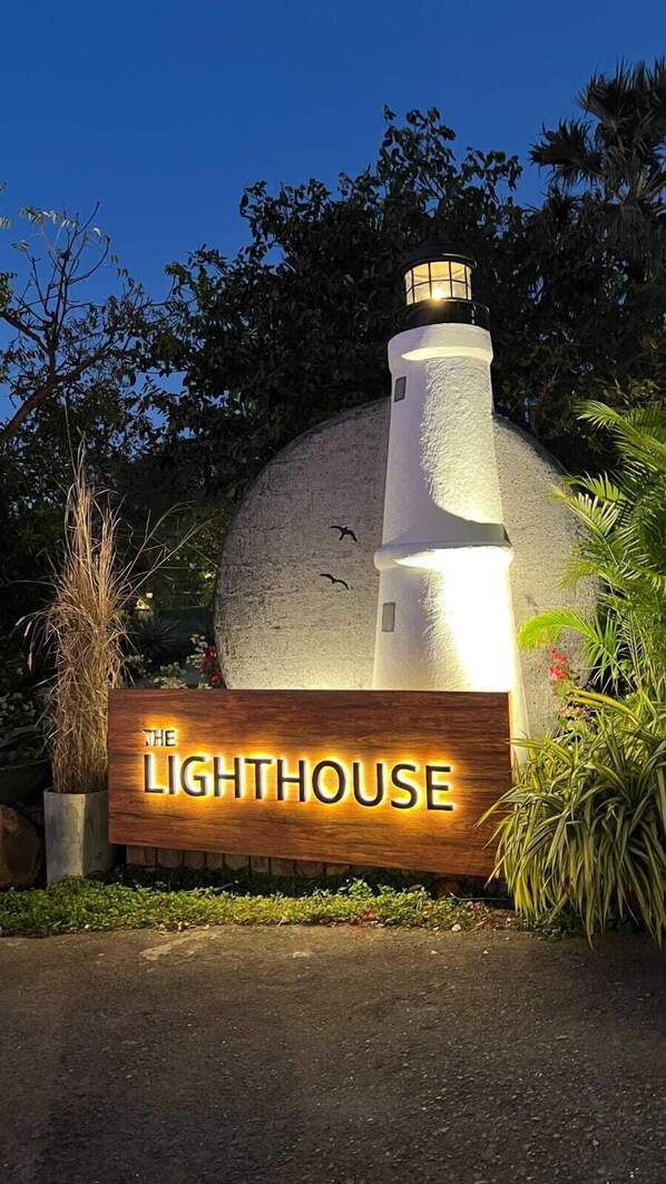 A lighthouse with a wooden sign that reads "The Lighthouse." - The Lighthouse (Mumbai)