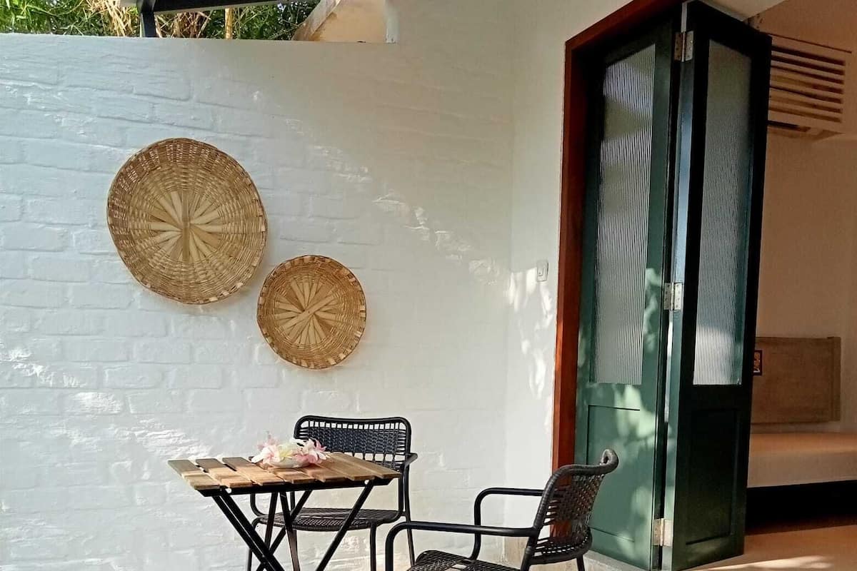 A patio with a table and two chairs, a white wall, and a sliding glass door.