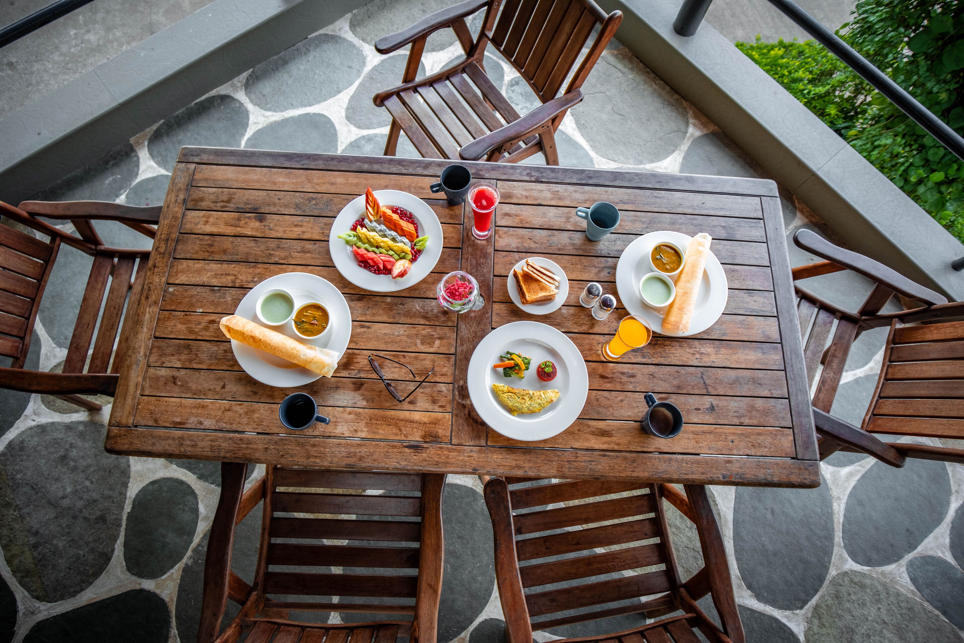 Una mesa de madera con platos de comida, vasos y cubiertos.