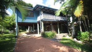 A two-story house with a balcony, surrounded by lush greenery and palm trees. - Magnetic Mango Escape (HORSESHOE BAY)