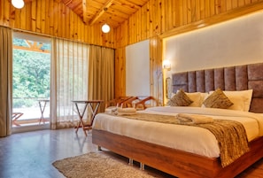 A wooden-paneled room with a large bed, a small table, and a view of the outdoors. - Qcent Woods Spa & Resort (Yamkeshwar)