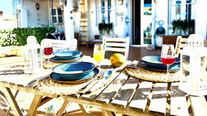Ein Außenbereich zum Essen mit Tischen für zwei Personen, ausgestattet mit gewebten Untersetzern und blauen Tellern.