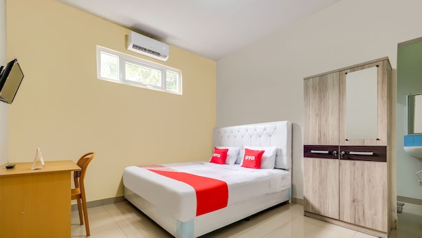 Una habitación de hotel con cama, escritorio, silla, armario y ventana.