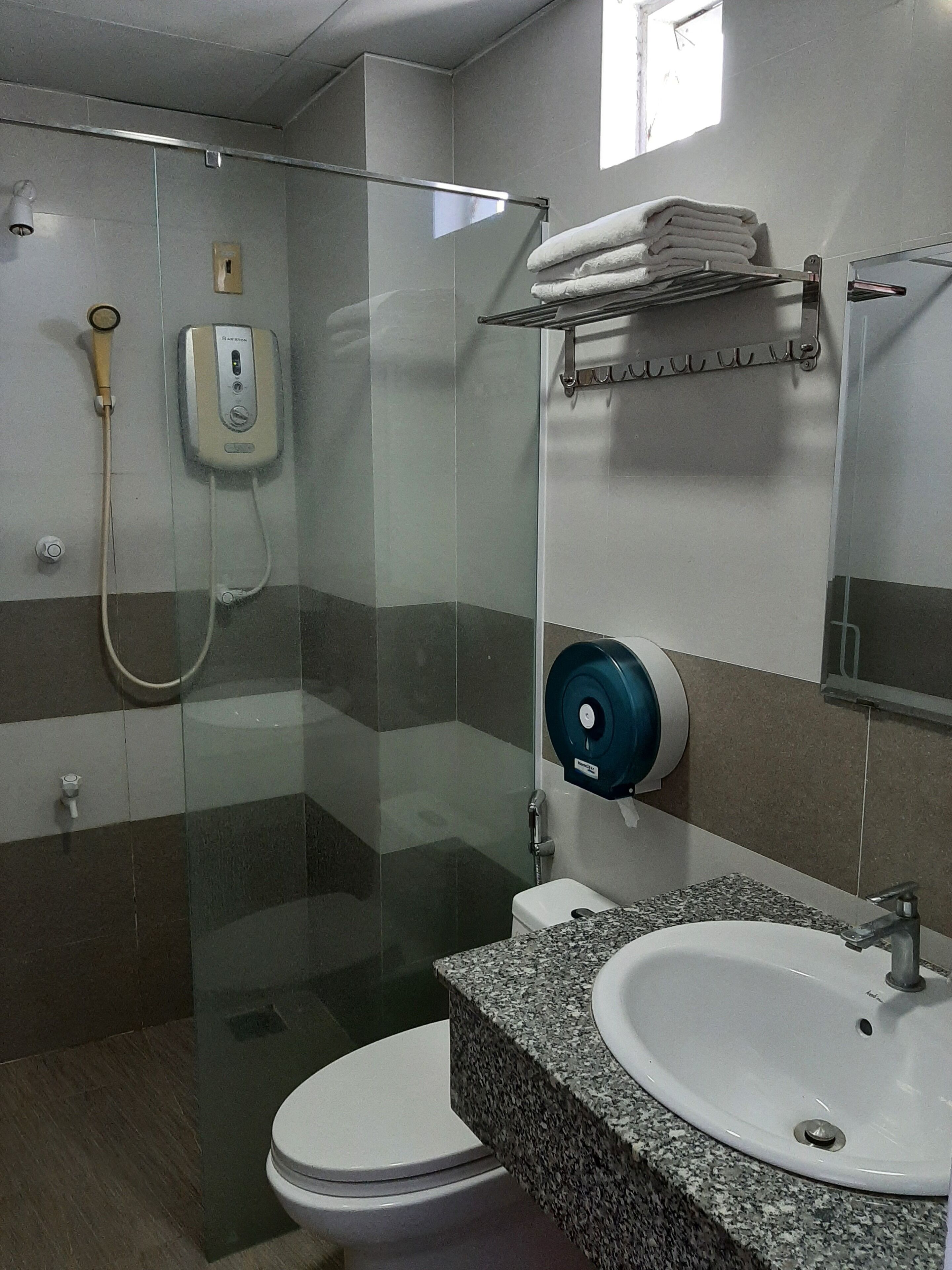 Un baño moderno con cabina de ducha de vidrio, inodoro blanco y lavabo sobre encimera de granito.