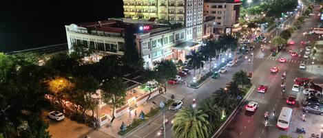 A multi-story hotel with a bar and restaurant on the ground floor, a parking area, and a busy street with vehicles and pedestrians.