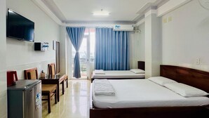 A hotel room with two beds, a TV, a refrigerator, and a balcony with blue curtains. - Anh Vy Hotel (Quy Nhon Nam)