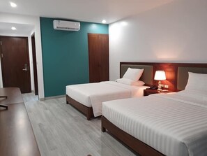 A hotel room with two beds, a desk, a wardrobe, and an air conditioning unit. - Ha Long Bay TC Hotel (Ha Long)