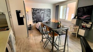 Una cocina funcional con zona de comedor, un amplio ventanal y un cuadro de la ciudad.