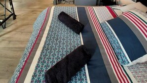 Habitación de hotel pequeña con cama, un escritorio, lavadora y espejo.