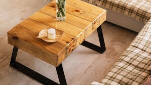 Une table basse en bois, sur laquelle se trouvent un vase de fleurs et un bol décoratif.