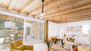 Un intérieur moderne avec un plafond en bois, un coin repas, un canapé et une cuisine.