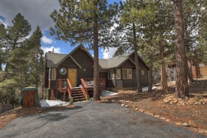 A cabin with a wooden exterior, a front porch, and a staircase leading to the entrance.