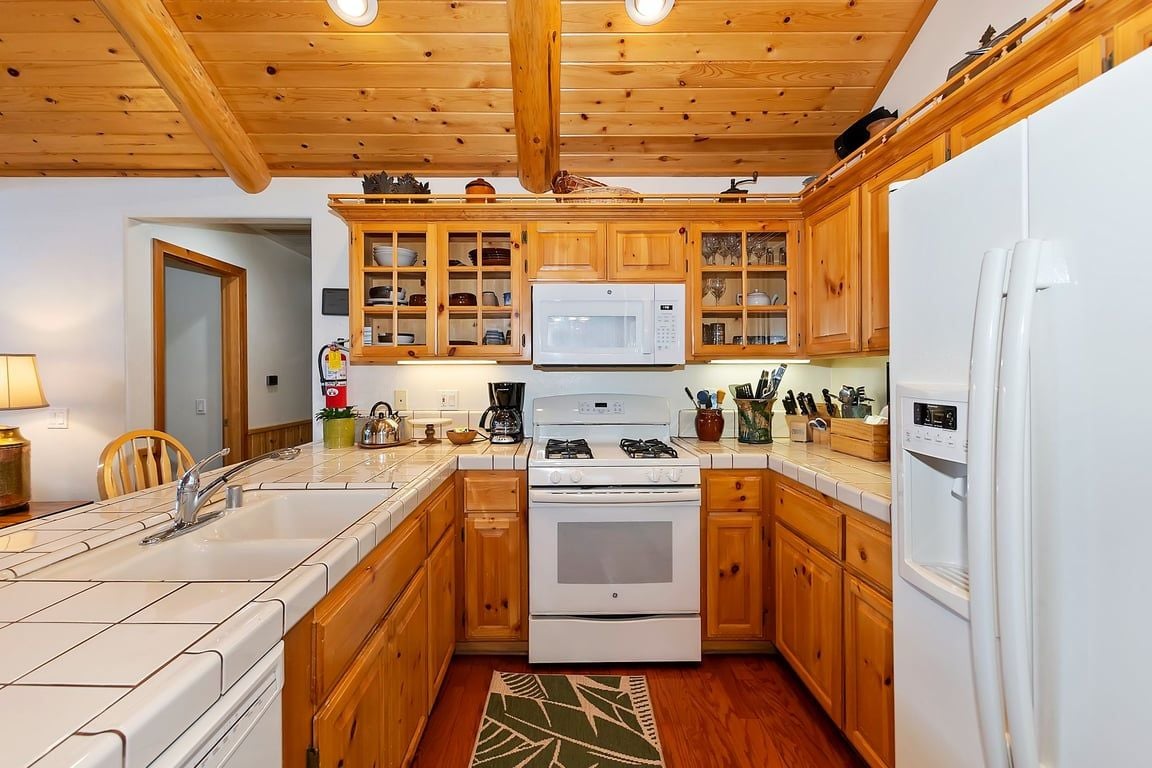 A kitchen with wooden cabinets, a microwave, stove, and refrigerator.