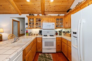 Cocina con gabinetes de madera, microondas, estufa y refrigerador.