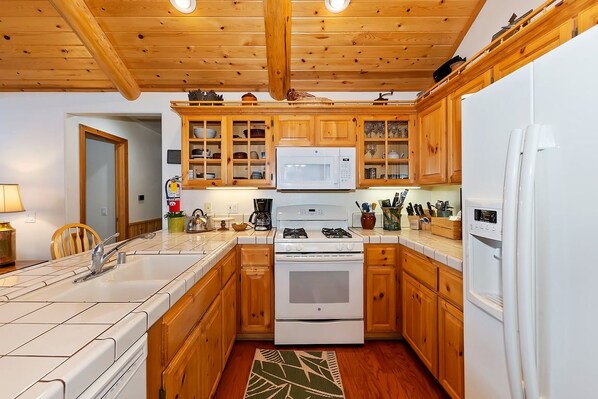 A kitchen with wooden cabinets, a microwave, stove, and refrigerator.
