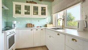 A kitchen with white cabinets, a coffee maker, a bread sign, and a window with a view of greenery. - Apartamenty Sun & Snow Dom Cayetano (gmina Wolin)