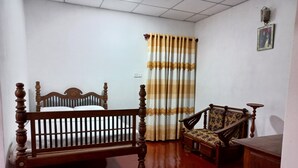A bedroom with a wooden bed, a chair, a desk, and a striped curtain. - Indra Sisila Villa Bentota  (Bentota)