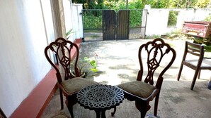 A patio with a round table and four chairs, a gate in the background, and a red bench to the right. - Indra Sisila Villa Bentota  (Bentota)