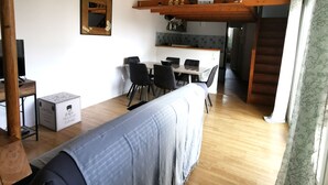 Una sala de estar acogedora con un sofá, un televisor y un comedor con sillas y una mesa.