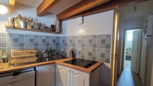 Una cocina con armarios blancos, un lavavajillas Bosch, encimera negra y azulejos decorativos en la salpicadero.