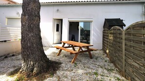 Una casa con mesa de picnic de madera, un árbol y una entrada protegida por una reja.