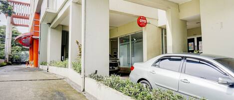 Un edificio con fachada blanca, un letrero rojo y un coche estacionado.