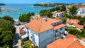 An aerial view of a coastal town with buildings, a marina, and a clear blue sky.