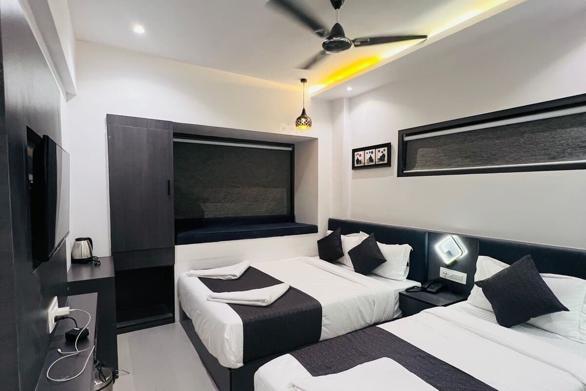 Ein modernes Hotelzimmer mit zwei Betten, einem Fernseher, einem Schreibtisch und einem Deckenventilator.
