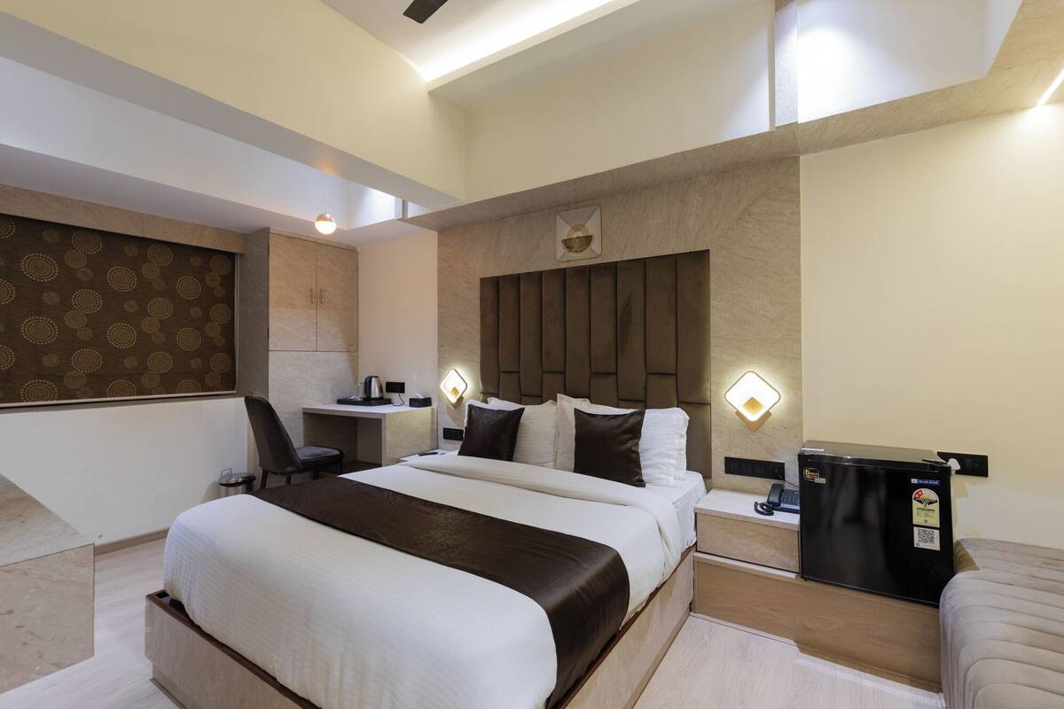 Ein modernes Hotelzimmer mit einem großen Bett, einem Schreibtisch, einem Stuhl und einem Kühlschrank.
