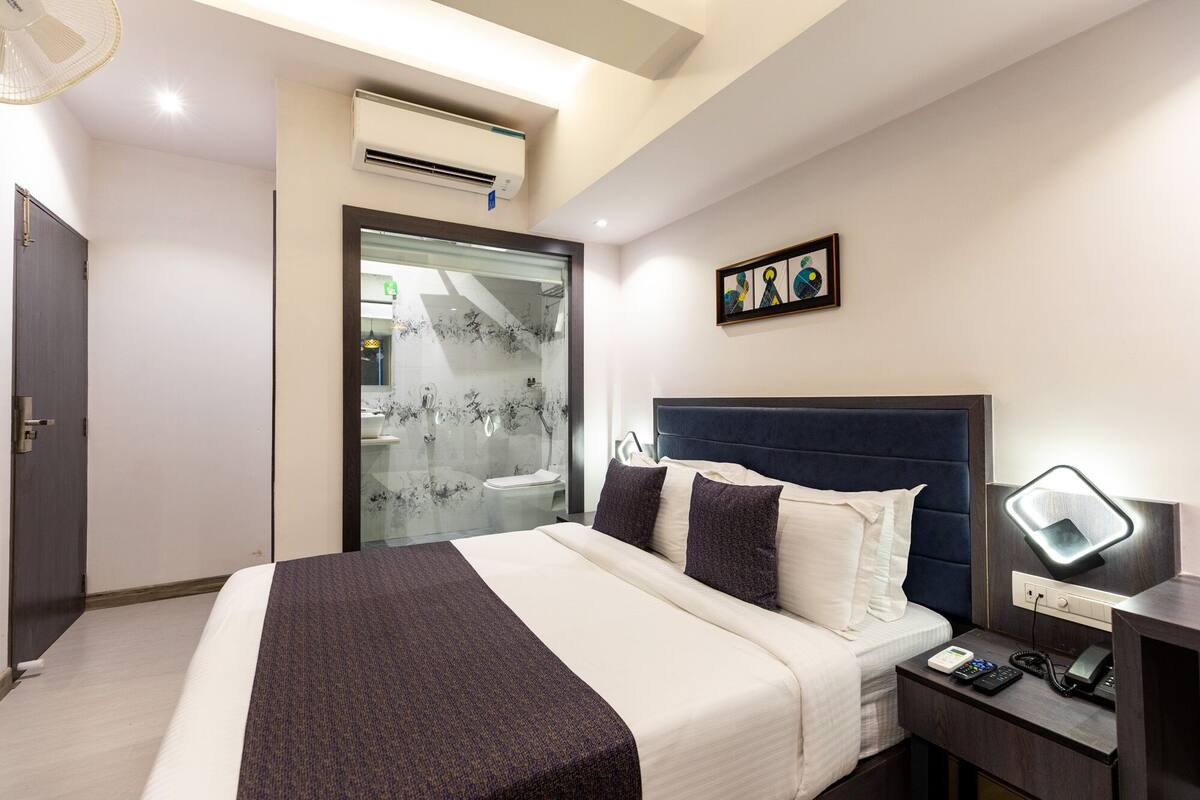 Ein Hotelzimmer mit Bett, Nachttisch und Schreibtisch mit Lampe.