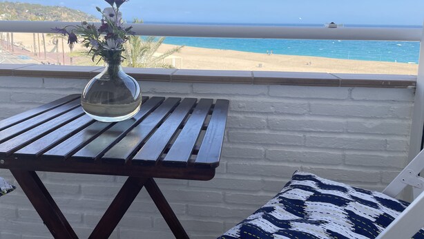 A balcony with a wooden table and a vase of flowers, overlooking a beach. - LLORET HIGH - PREMIUM (Lloret de mar)