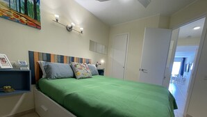 A bedroom with a green bedspread, a headboard with a striped pattern, a bedside table with a lamp, and a painting on the wall. - LLORET HIGH - PREMIUM (Lloret de mar)
