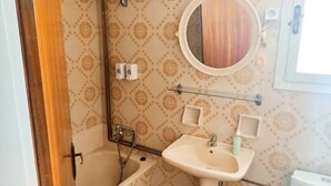 Ein Badezimmer mit einer Badewanne, einem Waschbecken, einem Spiegel und einer Toilette.