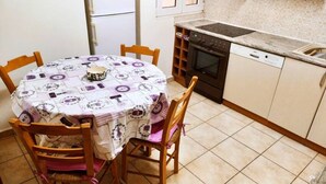 Eine kleine Küche mit Esstisch, Stühlen, Herd und Geschirrspüler.