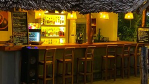 A bar area with wooden chairs, a bar counter, and a poolside view. - Shamba Village Hotel (Paje)