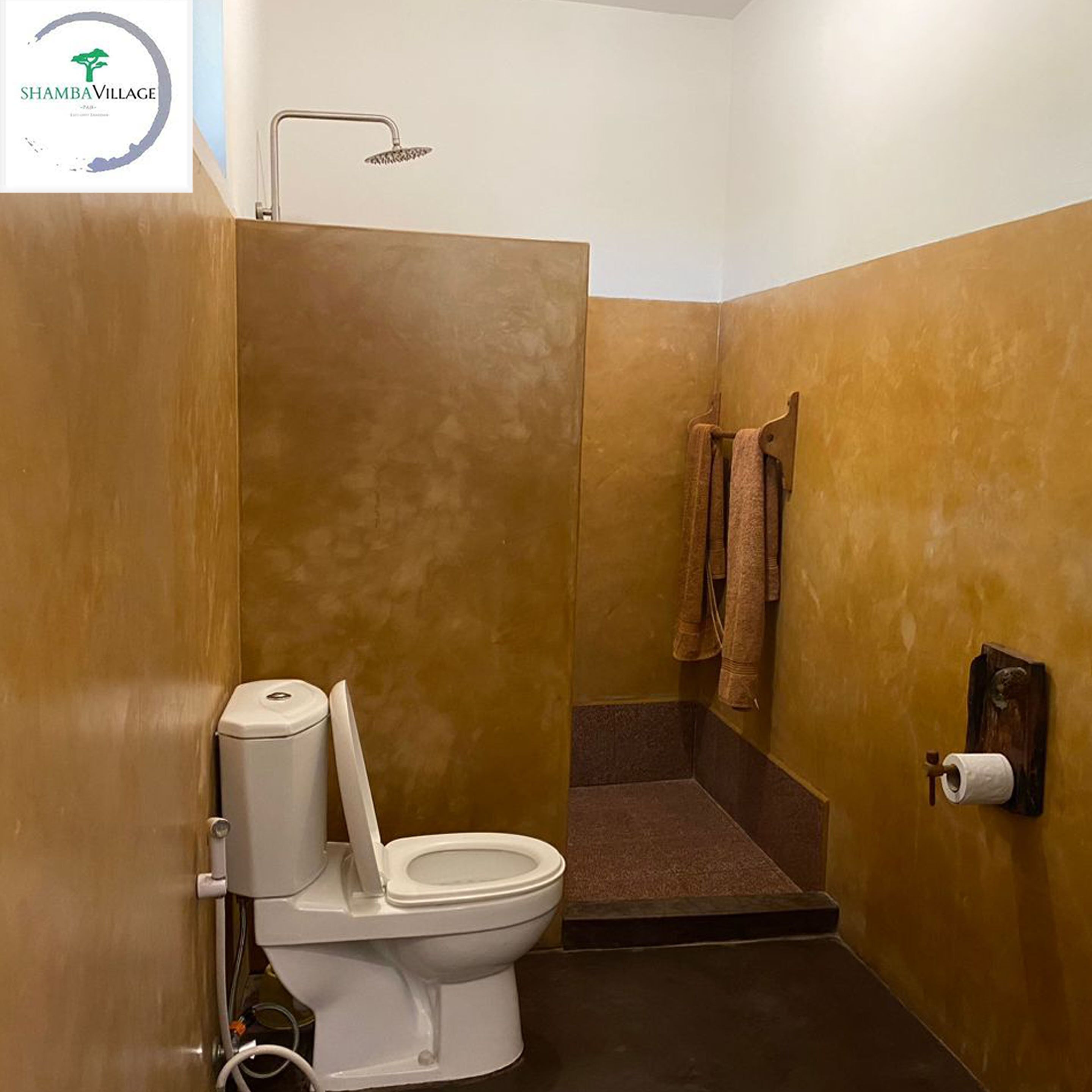 Et badeværelse med toilet, bruser og et håndklædestativ.