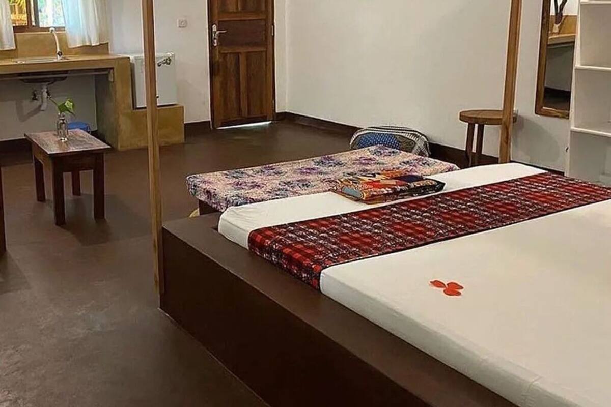 A hotel room with a bed, a small table, a chair, and a desk with a computer.