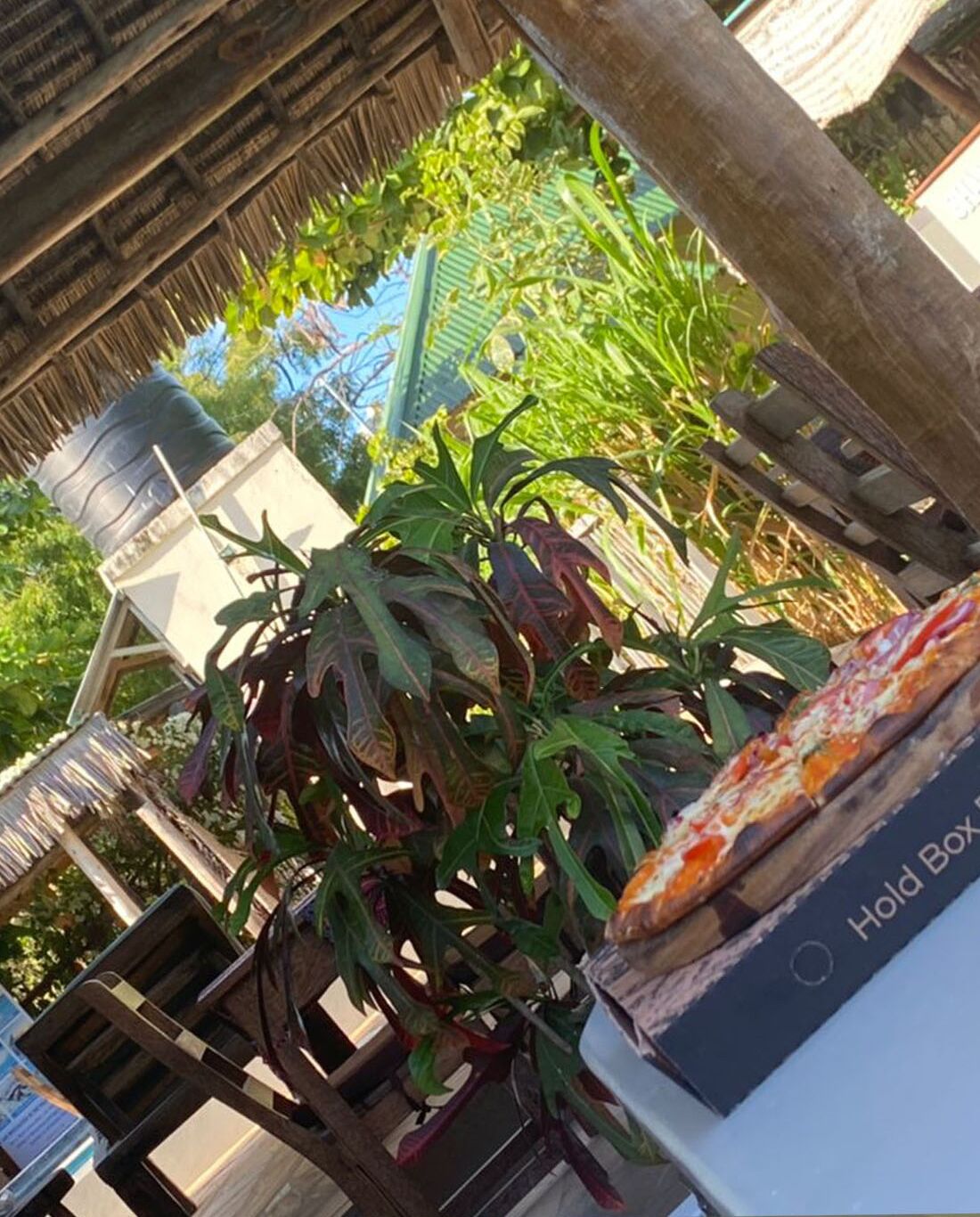A rustic outdoor seating area with a pizza on a box labeled "Hold Box."