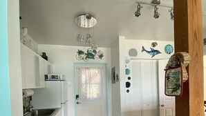 A kitchen with white cabinets, a stove, and a sink. There is a door with a blue frame and a window with a curtain. - Oceanfront Beach Luxury Retreat (St Thomas)