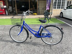 Una bicicleta blava aparcada sobre una superfície pavimentada, amb un cistell al capdavant.