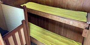 Un llit superposat amb matalàs groc i estructura de fusta.