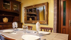 Une table à manger dressée avec des assiettes, des couverts et des verres, avec un miroir et un meuble en arrière-plan.