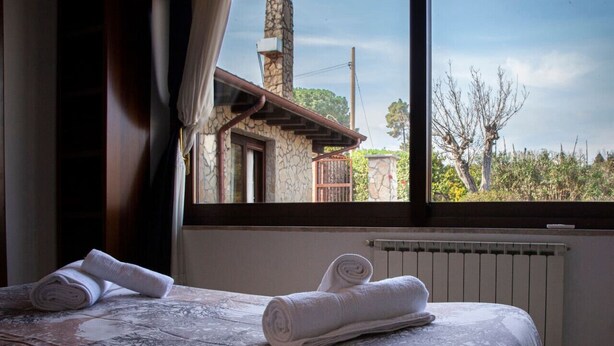 Une chambre avec deux lits, une cheminée en pierre et une vue sur les arbres et un bâtiment à l’extérieur.