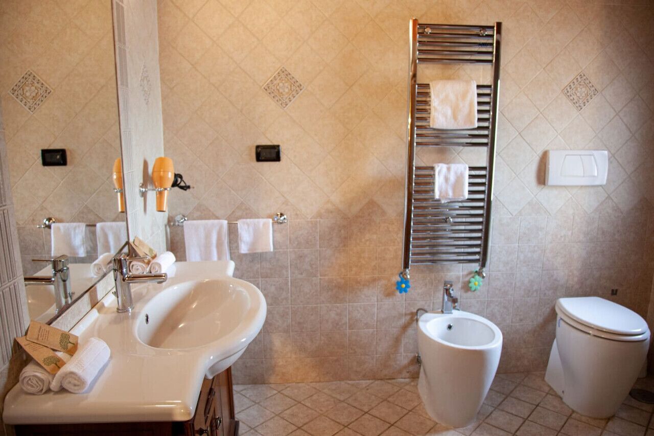 A bathroom with a sink, bidet, and toilet. There are towels and toiletries on the sink.