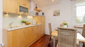 Una cocina moderna con armarios de madera, microondas y comedor con sillas de mimbre y una mesa.