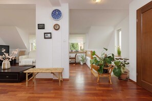 A spacious living area with a wooden bench, a coffee table, and a large potted plant. - Family House with Garden | 2 Bedrooms, Parking. (Warszawa)