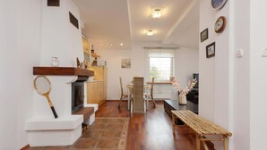Un amplio salón con chimenea, una mesa de comedor y un banco.